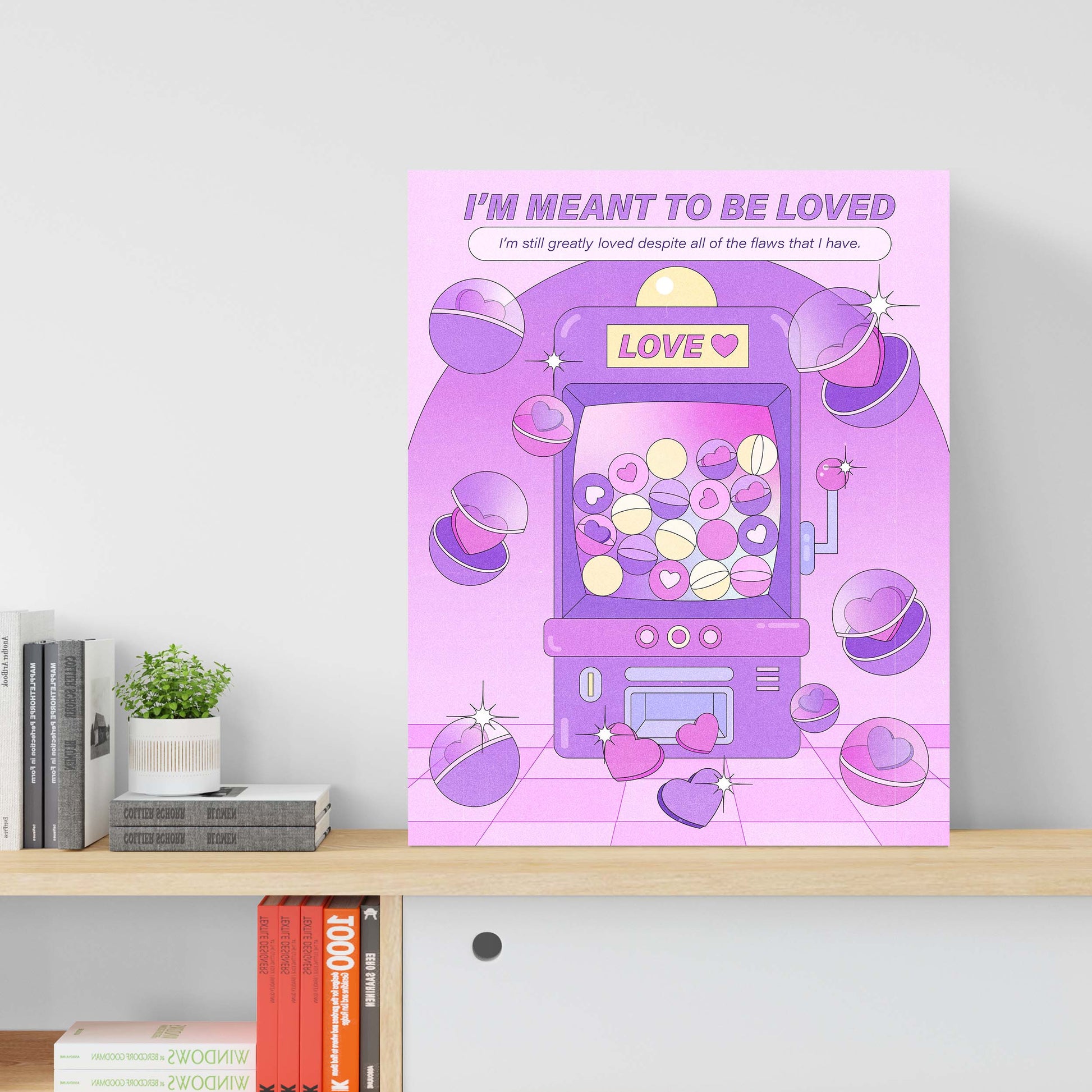 A purple claw machine self-care art print with the text "i'm meant to be loved" on a table